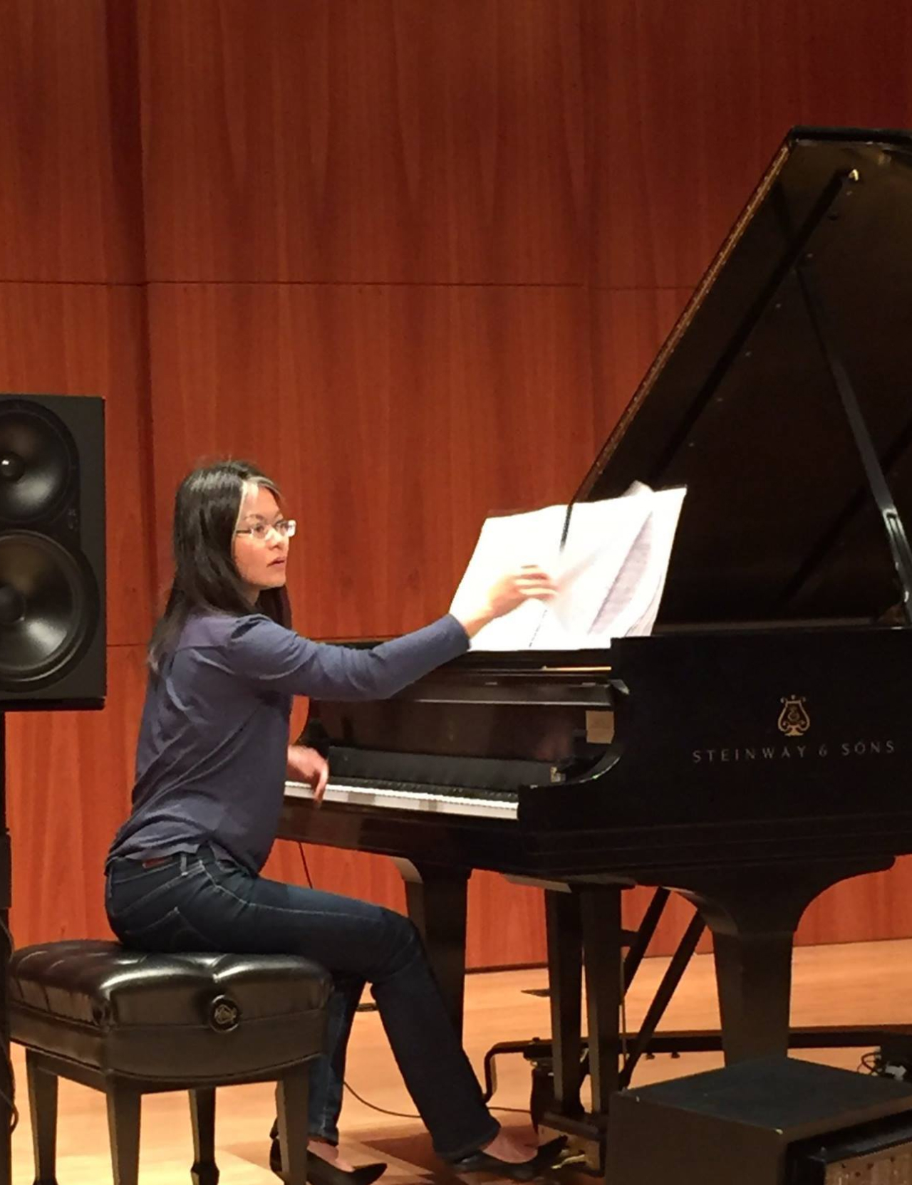 Shiau-uen Ding turning a music page while she's playing a steinway grandpiano